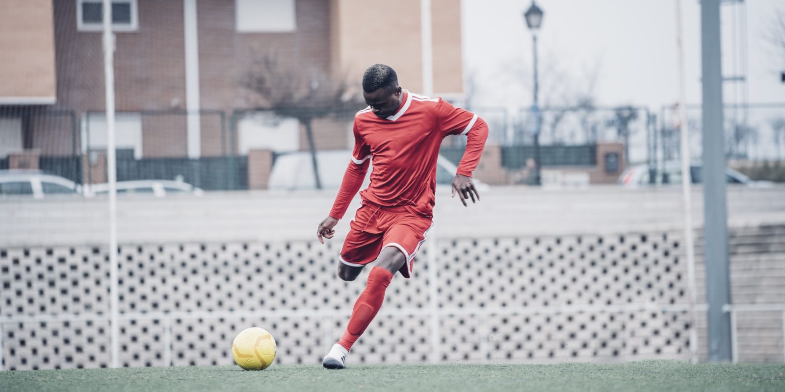 African soccer player with red outfit playing soccer.