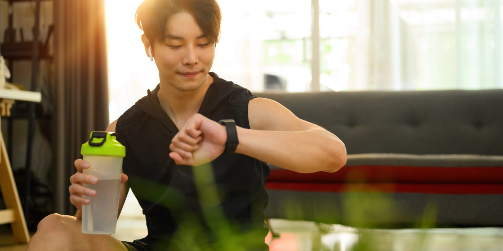 Muscular man in sportswear resting and checking his performance on fitness smart watch.