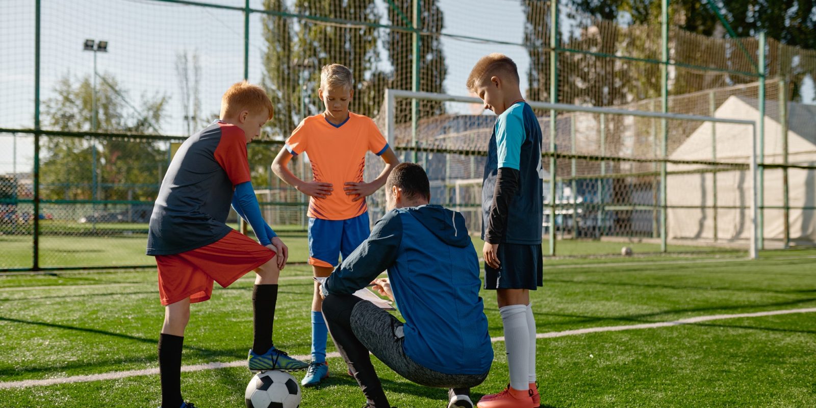 Soccer coach reviewing strategies with young boys soccer players